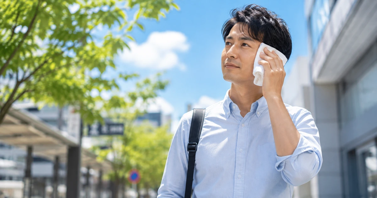 夏のデート前にハンカチで汗を拭き、身だしなみを整える男性。夏デートの汗・体臭対策を解説するアイキャッチ画像